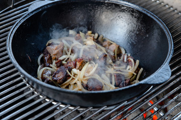 Pieces of lamb with onion are fried in boiling oil on the fire. As a stage in the preparation of...