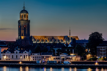 Obraz premium Evening twilight long exposure of the riverside promenade in Deventer, Netherlands, with IJssel river and St. Lebuinus Church.