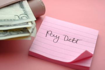 pay debt word on notepad with coins on table 