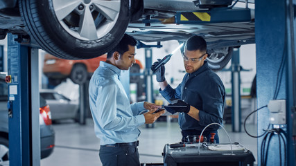 Manager Checks Data on a Tablet Computer and Explains the Breakdown to a Mechanic. Car Service...