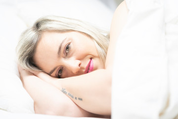 Portrait of an attractive woman smiling in a bed with white clothes