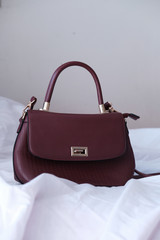 empty fashion leather handbag on bed, close up 