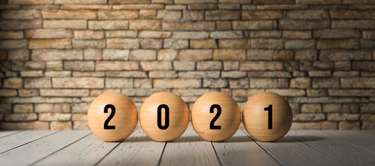 wooden spheres with number 2021 in front of a brick wall on wooden surface