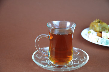 Tasty oriental sweets baklava, turkish delight on a plate on a dark black brown background and glasses of tea