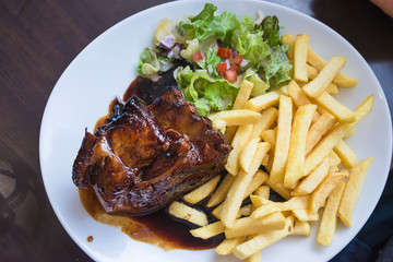 Plate with pork steak, french potatoes and green salad