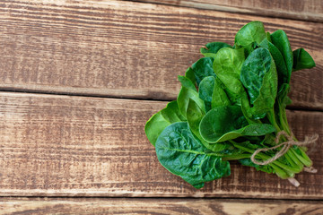 Clean food concept. Leaves of ripe juicy freshly picked organic spinach greens on a wooden...