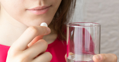 Closeup on young housewife eating pills and drinking water