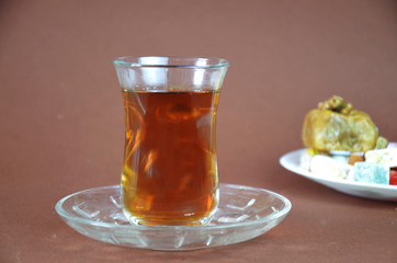 Tasty oriental sweets baklava, turkish delight on a plate on a dark black brown background and glasses of tea