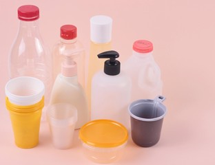 Mother Earth Day. Plastic pakaging concept.group of empty transparent plastic bottles and cups on pink background.Front view with copy space