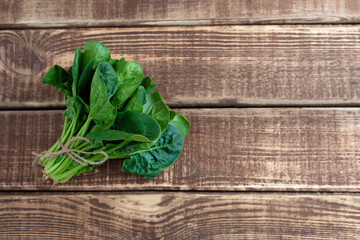 Clean food concept. Leaves of ripe juicy freshly picked organic spinach greens on a wooden background. Healthy detox spring-summer diet. Vegan Raw Food. Copy space.