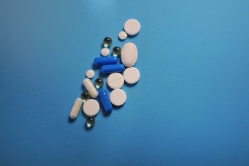 A lot of different pills on blue table. Medicine against COVID-19 and diseases