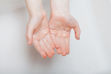 Fototapeta premium The child washes his hands thoroughly in the home bathroom.