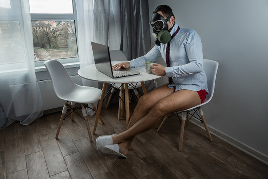 The Manager works at home under quarantine. Business and the coronavirus pandemic. In a shirt and tie but no pants. Works at home on a laptop with coffee. Working remotely. 