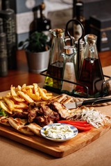 Chicken kontosouvli marinated with fresh herbs with potato fires and crunchy pita bread, thin sliced tomatoes and white onion on the side. Main course authentic greek cuisine.