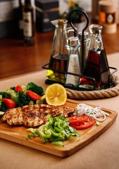 Mediterranean cuisine main course presentable plating on casual dine in background. Traditional greek chicken chop with fresh steamed vegetables photography for greek restaurant menu concept.