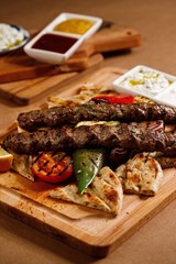 Savory lamb kebab served with pita bread and grilled cherry tomatoes.. Authentic greek cuisine in presentable plating. Authentic greek cuisine photography in presentable plating.