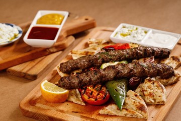 Savory lamb kebab served with pita bread and grilled cherry tomatoes.. Authentic greek cuisine in presentable plating. Mediterranean cuisine main course photography. - 341437494