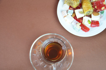 Tasty oriental sweets baklava, turkish delight on a plate on a dark black brown background and glasses of tea