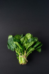 Clean food concept. Bunch of leaves of fresh organic spinach greens on a black background. Healthy...
