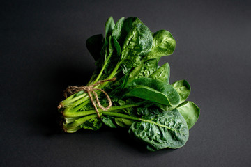 Clean food concept. Bunch of leaves of fresh organic spinach greens on a black background. Healthy...