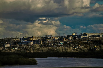 Heavy rain clouds slowly floating above the city on the banks of the river