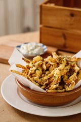 Potato crisps with herbs on a brown presentable plating. Authentic Mediterranean cuisine photography in a wooden background.