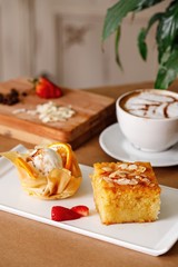 Freshly baked bread with variety of toppings on a wooden tray in casual dine in table background with coffee latte. And cheese cubes. Authentic Mediterranean cuisine photography concept.