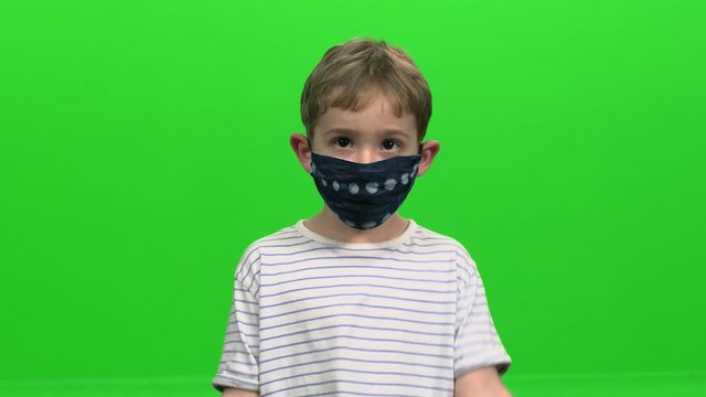 Little Boy with face mask demonstrates various emotions: Confused, angry, happy over green screen.