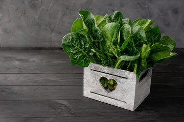 Clean food concept. Leaves of fresh organic spinach greens in a wooden box on a black background. Healthy detox spring-summer diet. Vegan Raw Food. Copy space.