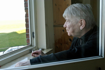 seniorin schaut aus fenster