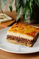 Mousaka potato ground beef, herbs topped with a light betcheamel with elassona cheese. Authentic Mediterranean main course dish photography for online delivery menu concept.