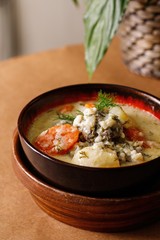 White cream and herbs soup with thin sliced tomatoes. Authentic Mediterranean appetizer dish photography on wooden table background.