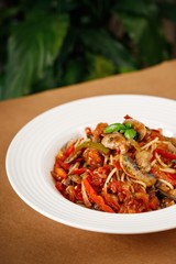 Greek pasta with mushroom, herbs and red sauce on white plate. Authentic Mediterranean main course dish photography.