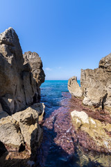 Fototapeta na wymiar Idyllic view over the turquoise sea from the rocky coastline on a sunny day in Cefalu, Sicily, Italy.