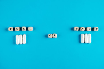 Wooden cubes on a blue background with letters. Choosing between facts and fake.