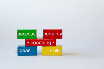 colorful blocks on a white background with the words: certainty, skills, ideas, success.In the middle the word coaching