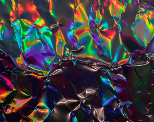 high res full frame macro photo of abstract crumpled iridescent holographic foil background with...