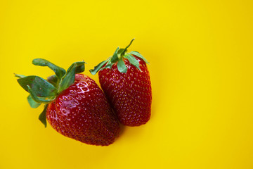 juicy red strawberries lies on a yellow background
