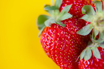 juicy red strawberries lies on a yellow background
