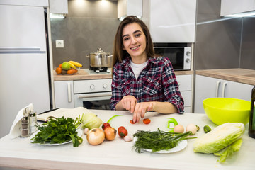 cute girl prepares a salad of different vegetables and greens for a healthy lifestyle.