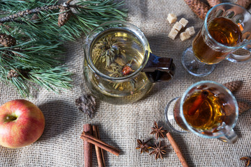 green tea beautifully brewed in a glass teapot outdoors in the forest with natural light with cinnamon sticks, anise and spruce cones