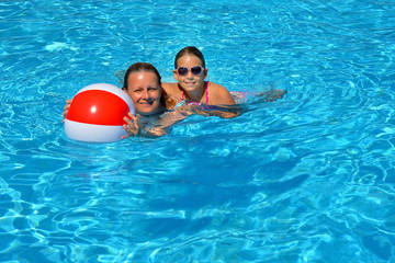 Female beauty relaxing in swimming pool with her daughter