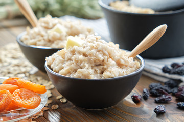 Bowls of healthy oatmeal porridge with dried apricots and raisins.
