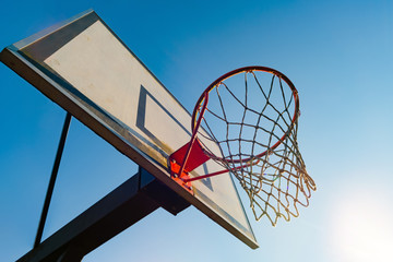 Street basketball hoop on a sunny day with blue sky in the background. Urban youth game. Concept of success, scoring points and winning © CrispyMedia