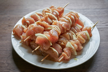 Raw chicken breast skewers with pieces of onion marinated in olive oil with greek style spices and herbs waiting to be placed on charcoal grill. Light and fresh snack, full of nutritions and proteins.