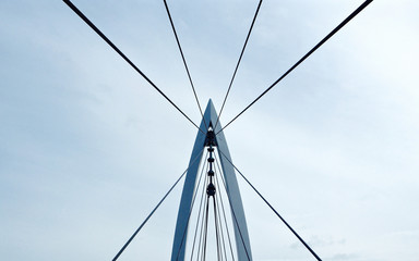 Contemporary style pedestrian suspension bridge over the Arkansas River taken in Wichita, KS where people can walk across the bridge with views of the river and city