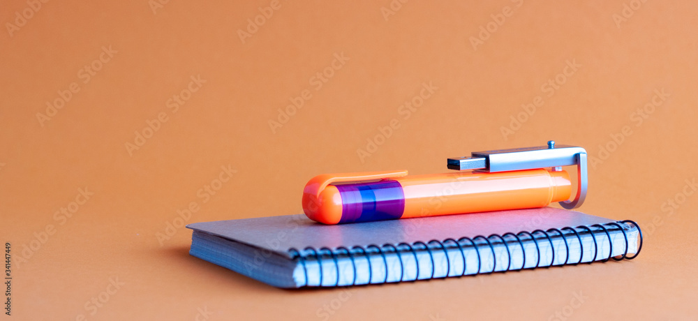 Poster colorful marker and flash drive on a paper notepad. the background is orange. concept.