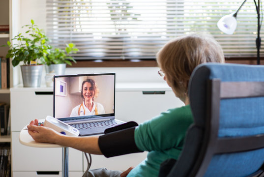telemedicine concept elderly woman speaking to her doctor online and taking her blood pressure