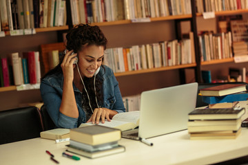 Female student study in the college library.She using laptop and learning online for university exam.	
