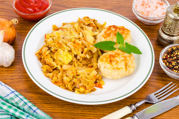 Stewed cabbage, meat cutlets, spices, salt on wooden table.